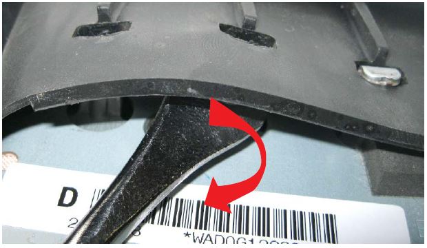 While pushing upward on the airbag module, insert a trim clip removal tool