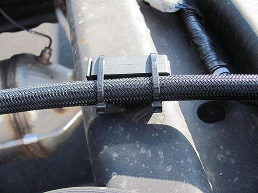 Using two wire ties, secure the transfer hose to the frame cross member clip